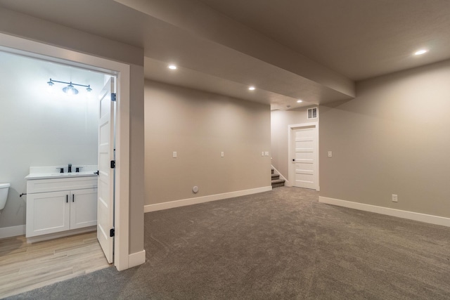 basement with sink and light carpet