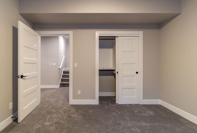 unfurnished bedroom featuring a closet and dark colored carpet