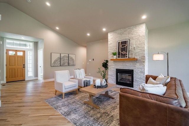 living room with a fireplace, high vaulted ceiling, and light hardwood / wood-style flooring