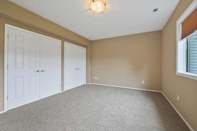 unfurnished bedroom featuring carpet and two closets