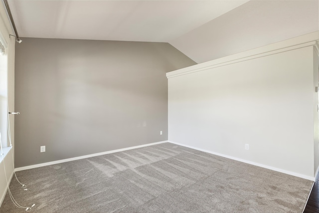 spare room featuring lofted ceiling and dark colored carpet