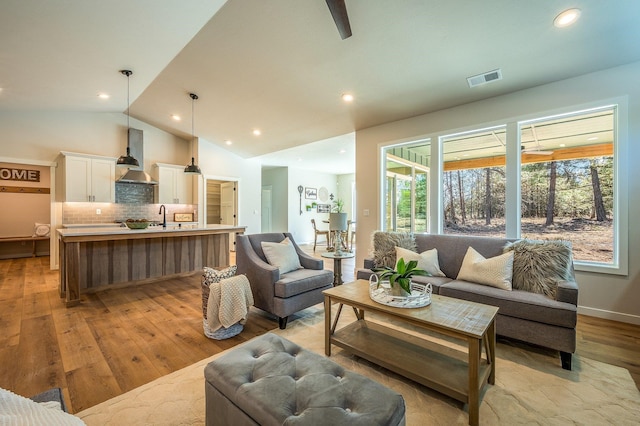 living room with light hardwood / wood-style flooring, lofted ceiling, and sink