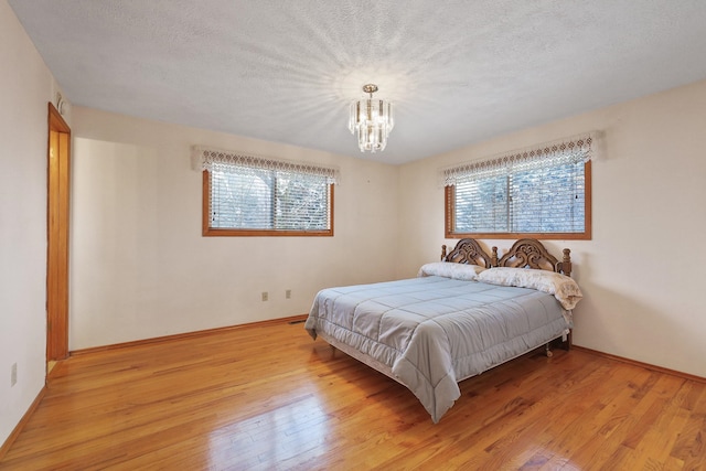 bedroom featuring an inviting chandelier, light hardwood / wood-style floors, and multiple windows