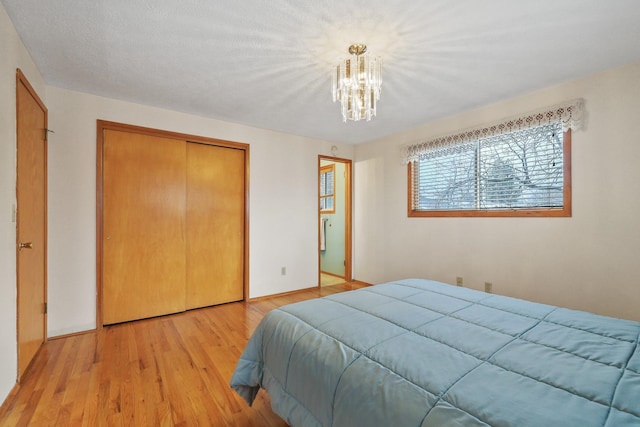 bedroom with light wood-type flooring, a chandelier, and a closet