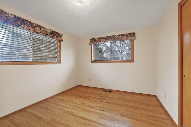 spare room featuring light hardwood / wood-style floors and a textured ceiling