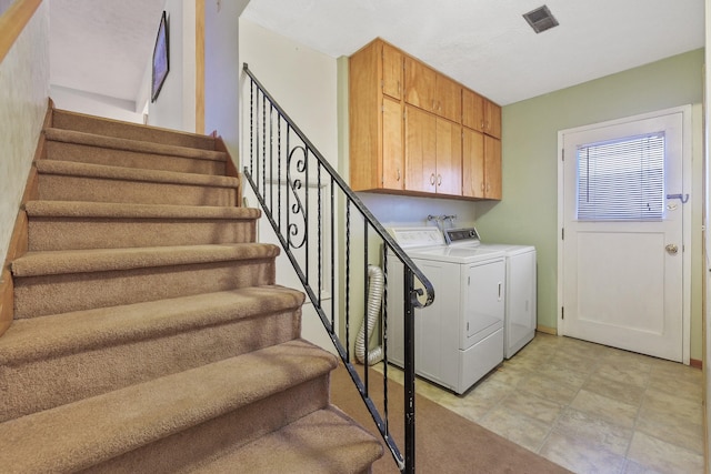 clothes washing area featuring cabinets and washer and dryer