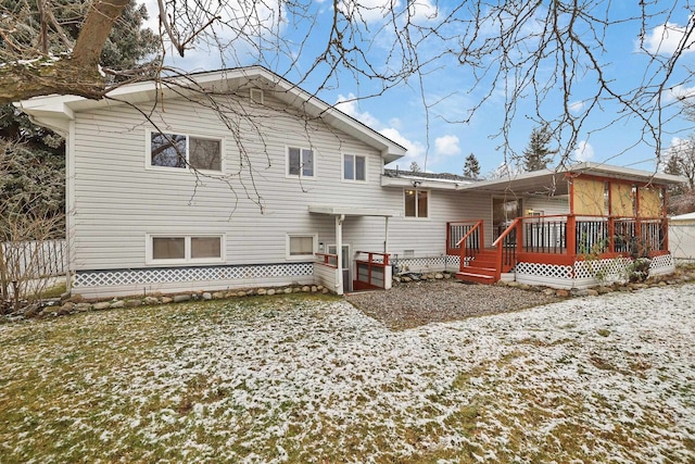 snow covered rear of property with a deck