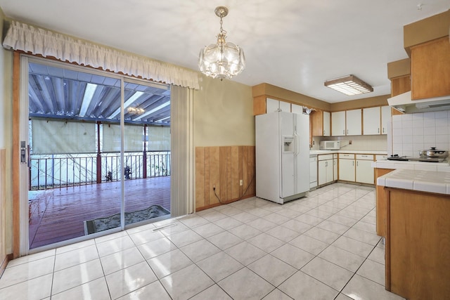 kitchen with white appliances, decorative backsplash, light tile patterned floors, and hanging light fixtures