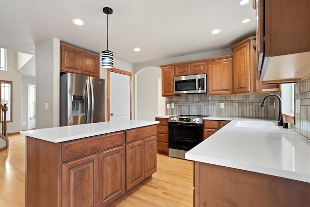 kitchen featuring backsplash, sink, light hardwood / wood-style flooring, appliances with stainless steel finishes, and a kitchen island