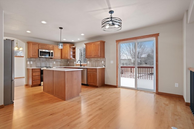 kitchen featuring sink, a center island, hanging light fixtures, tasteful backsplash, and appliances with stainless steel finishes