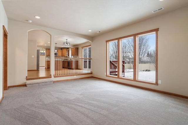 unfurnished living room with light colored carpet and an inviting chandelier