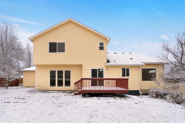 snow covered back of property with a wooden deck