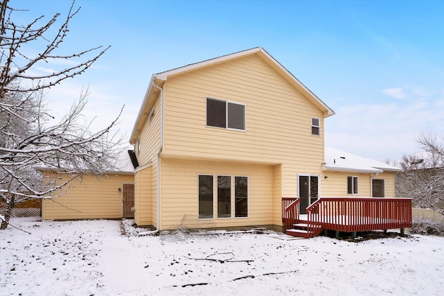 snow covered back of property with a wooden deck