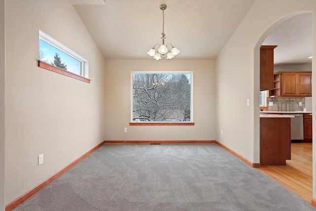 unfurnished dining area featuring light colored carpet and an inviting chandelier