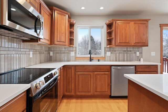 kitchen with decorative backsplash, sink, stainless steel appliances, and light hardwood / wood-style flooring