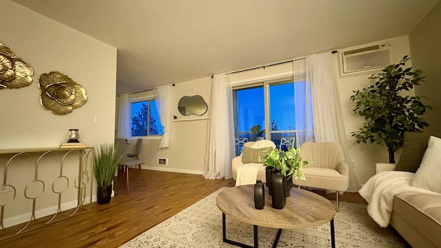 living area featuring wood-type flooring and a wall unit AC