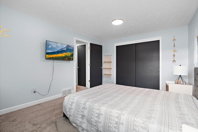 bedroom with carpet, a textured ceiling, and a closet