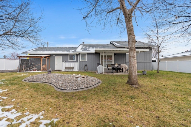 back of property featuring a patio area, a yard, and solar panels