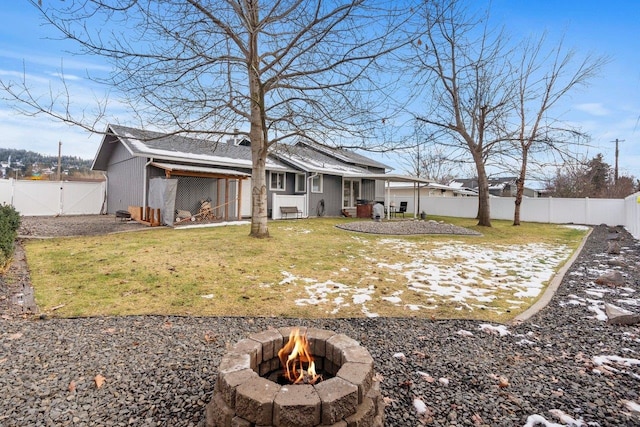 rear view of property with a yard and an outdoor fire pit