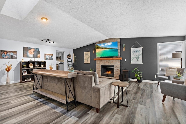 living room featuring a stone fireplace, hardwood / wood-style floors, and lofted ceiling