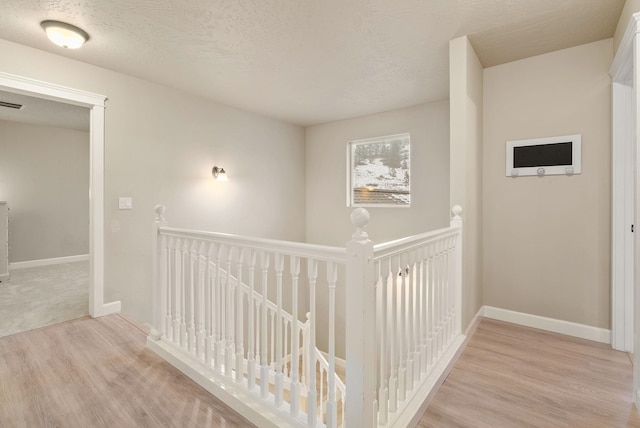 hallway featuring light hardwood / wood-style flooring and a textured ceiling