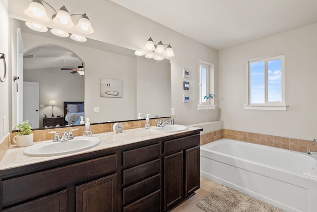 bathroom with ceiling fan, vanity, and a bath