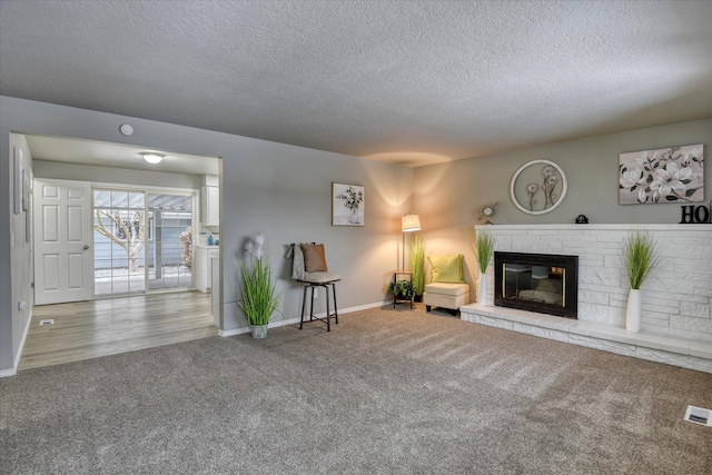 sitting room featuring carpet, a textured ceiling, and a brick fireplace