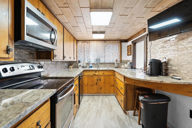 kitchen featuring light stone countertops, stainless steel appliances, tasteful backsplash, and sink