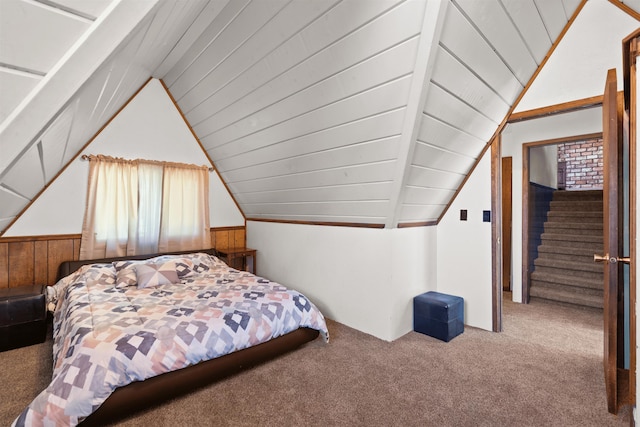 carpeted bedroom with vaulted ceiling and wood walls