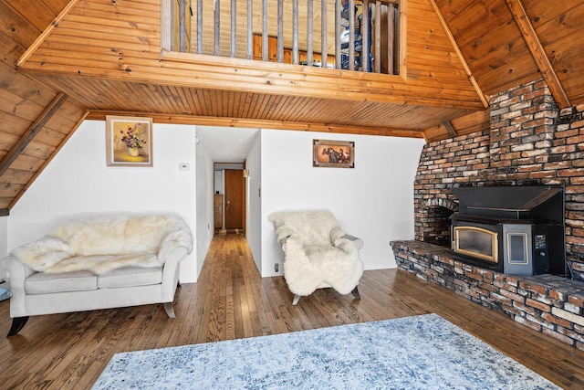 living room featuring dark hardwood / wood-style flooring, a wood stove, vaulted ceiling, and wood ceiling