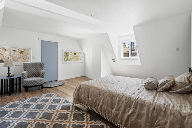 bedroom with hardwood / wood-style flooring, multiple windows, and lofted ceiling