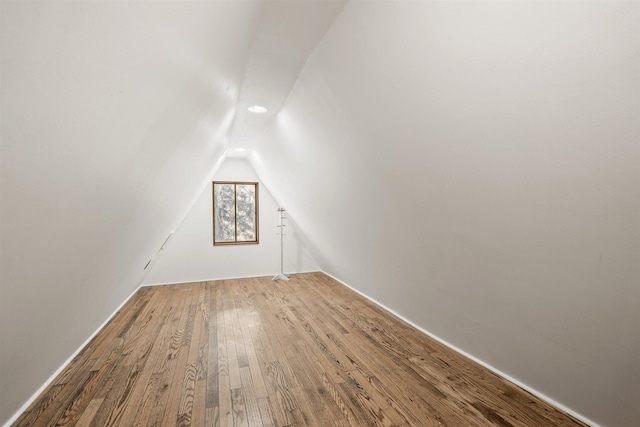 additional living space with hardwood / wood-style flooring and lofted ceiling