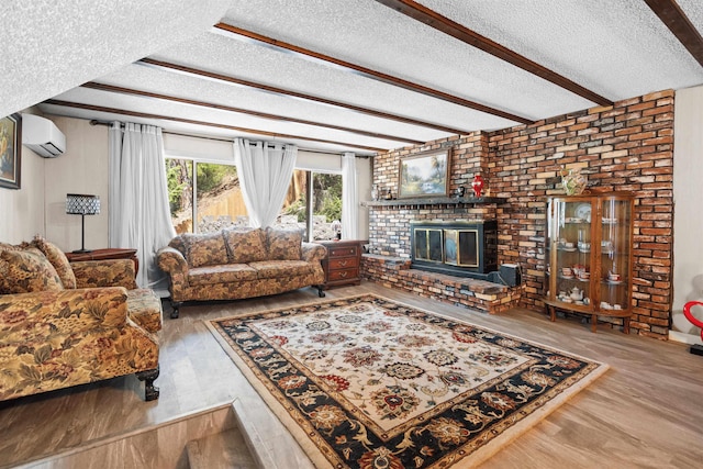 living room with a textured ceiling, a wall unit AC, beam ceiling, a fireplace, and hardwood / wood-style floors