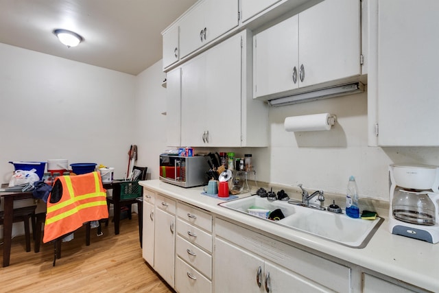 kitchen featuring white cabinets, light hardwood / wood-style floors, and sink