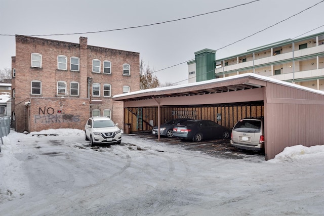 snow covered parking area featuring a carport