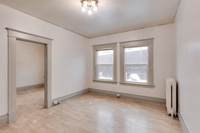 spare room featuring light wood-type flooring and radiator