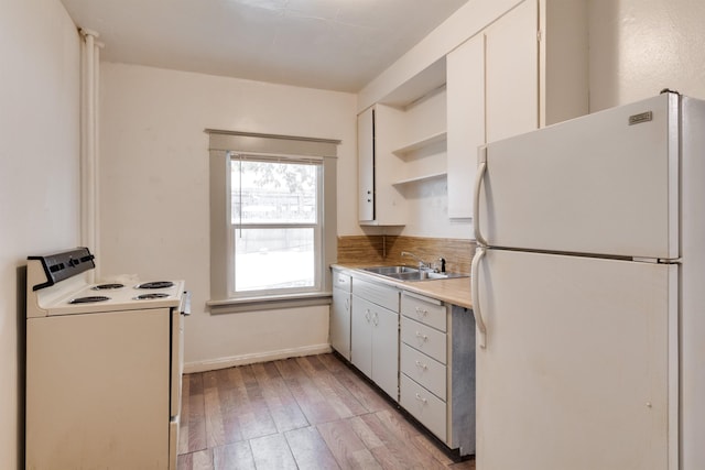 kitchen with white cabinets, white appliances, light hardwood / wood-style floors, and sink