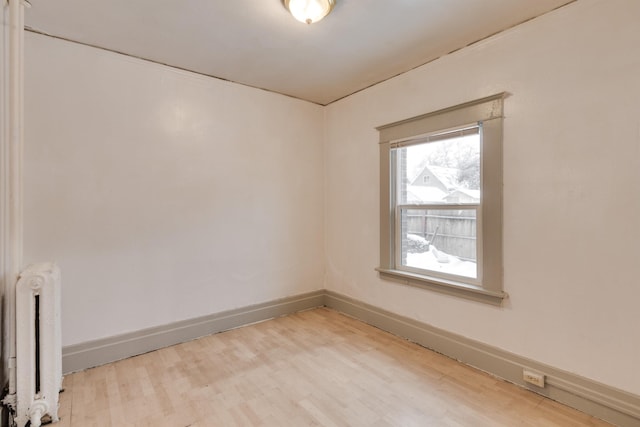 spare room with radiator heating unit and wood-type flooring