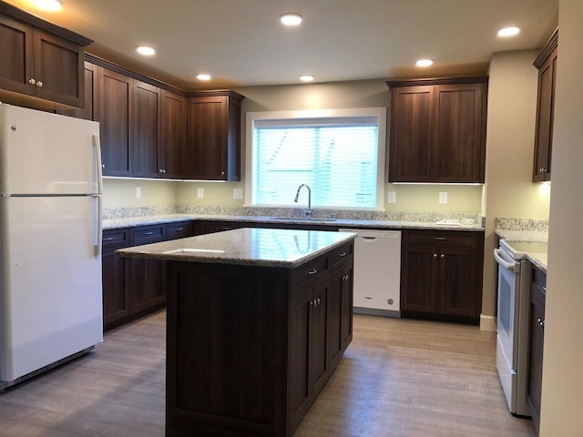 kitchen featuring dark brown cabinets, white appliances, sink, light hardwood / wood-style flooring, and a kitchen island