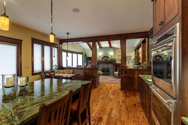 dining room with a fireplace, lofted ceiling with beams, and hardwood / wood-style flooring