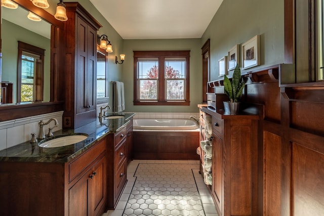 bathroom featuring tile patterned flooring, vanity, and tiled tub