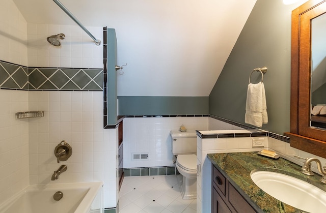 full bathroom featuring vanity, tile patterned floors, tiled shower / bath, toilet, and tile walls