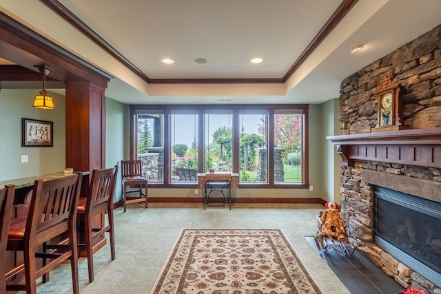 living area featuring a raised ceiling, a stone fireplace, light carpet, and crown molding