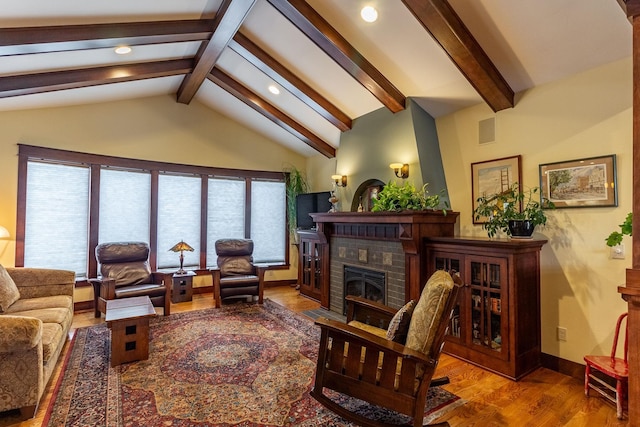 living room with hardwood / wood-style flooring, vaulted ceiling with beams, and a fireplace