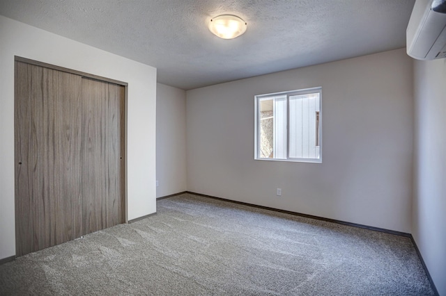 unfurnished bedroom with a wall mounted air conditioner, carpet flooring, a closet, and baseboards