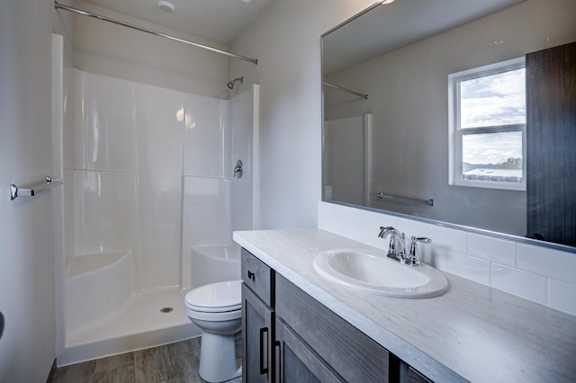 full bathroom featuring toilet, a shower, wood finished floors, vanity, and decorative backsplash