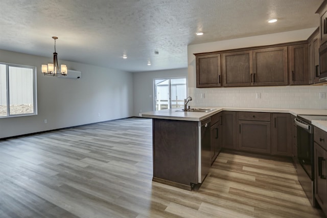 kitchen featuring a sink, a peninsula, a textured ceiling, and light wood-type flooring
