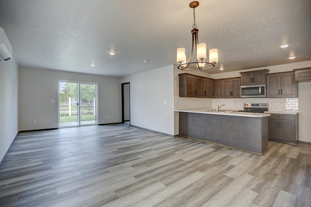 kitchen featuring light wood-style flooring, an inviting chandelier, open floor plan, tasteful backsplash, and appliances with stainless steel finishes