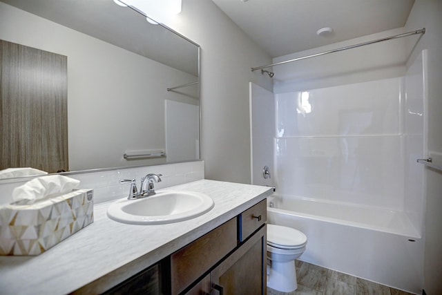 bathroom featuring toilet, wood finished floors, washtub / shower combination, tasteful backsplash, and vanity