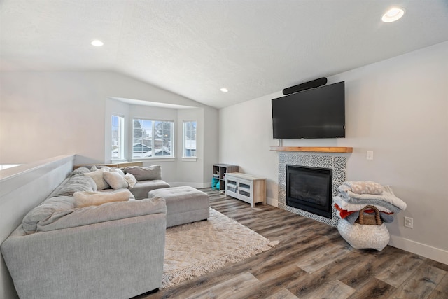 living room featuring a tile fireplace, a textured ceiling, hardwood / wood-style flooring, and lofted ceiling